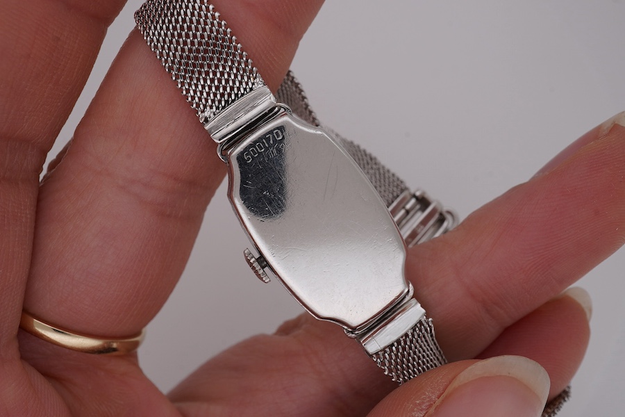 A lady's mid 20th century Swiss white metal(platinum mark) and diamond set cocktail watch with 'tumbling' Arabic numeral dial, on a 9ct white metal mesh link bracelet, case diameter 16mm, overall length 16cm, gross weigh